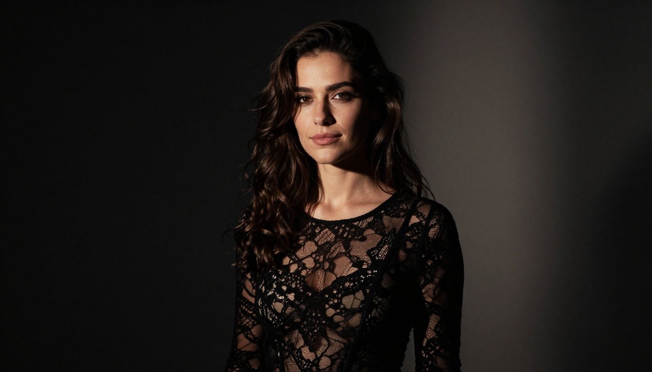 Mysterious brunette woman in black lace top looking over her shoulder with dramatic chiaroscuro studio lighting