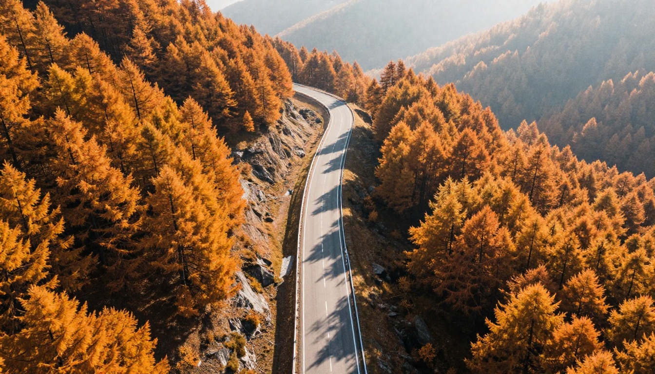 An aerial view of a pearl white crossover on a winding autumn mountain road